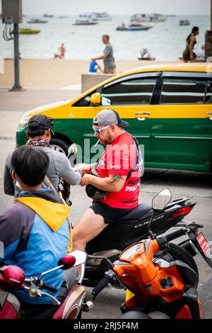 Un homme obtient son permis de conduire vérifié tout en conduisant sa moto le long de Beach Rd. Pattaya, Thaïlande. Banque D'Images