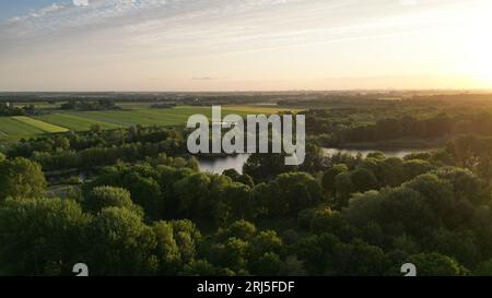 Un paysage pittoresque de collines parsemées d'arbres sertis contre le ciel de coucher du soleil Banque D'Images