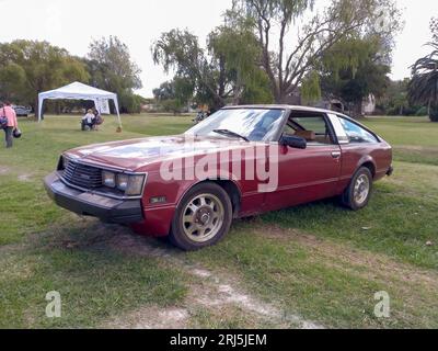 Vieux rouge bordeaux Toyota Celica série B coupé circa 1980 sur la pelouse. Nature, herbe, arbres. CAACMACH 2023 salon de voitures anciennes. Banque D'Images