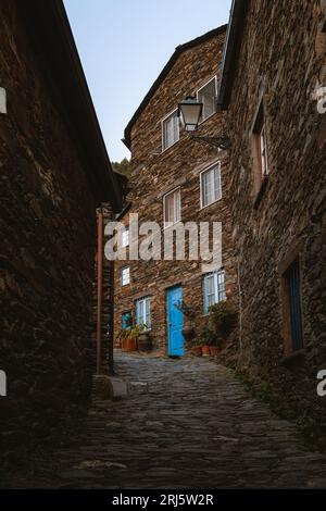 Une porte bleue installée sur fond d'une rangée de maisons en briques et de plantes en pot à Piodao, Portugal. Banque D'Images