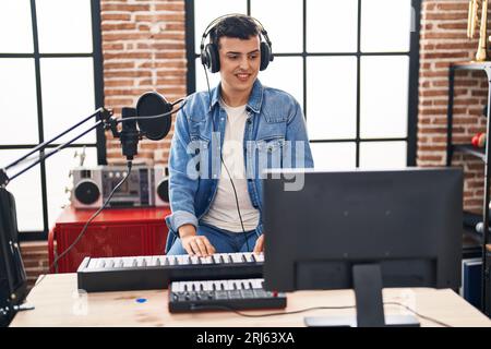 Jeune homme non binaire musicien jouant un clavier de piano dans un studio de musique Banque D'Images