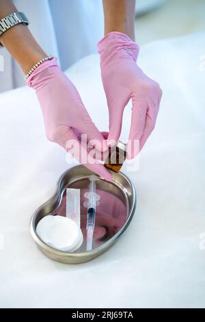 Mains de femme cosmétologue méconnaissable remplissant la seringue avec une solution pour le traitement de soins de la peau. Banque D'Images