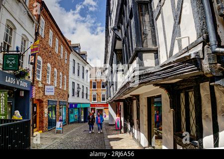 Shrewsbury, Shropshire, Angleterre, Royaume-Uni - les gens marchent entre les magasins devant le bâtiment à ossature de bois de Abbots House sur une rue étroite appelée Butcher Row Banque D'Images