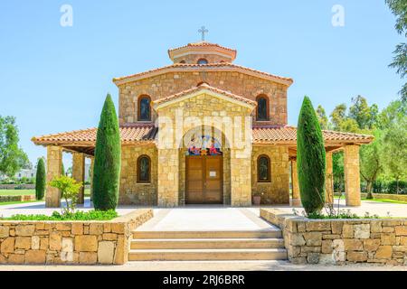 Une vue extérieure d'un bâtiment religieux avec une structure attenante comportant trois vitraux au premier plan : l'église de Halkidiki Banque D'Images