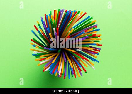 Vue de dessus de nombreux tubes à cocktail en plastique multicolore dans un verre.Pailles à boire de couleurs vives isolées sur fond blanc. Banque D'Images