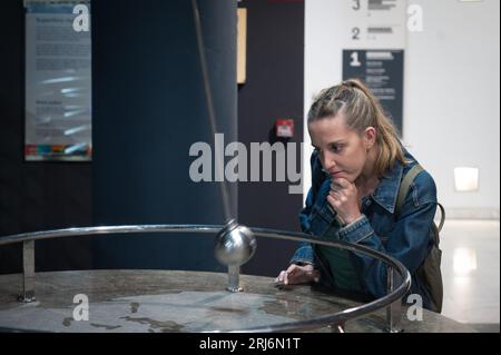 Jeune fille dans le laboratoire des sciences du musée jouant avec le pendule Banque D'Images