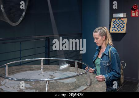 Jeune fille dans le laboratoire des sciences du musée jouant avec le pendule Banque D'Images