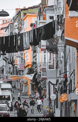Cette photo montre un groupe de personnes marchant dans la ville, en bas d'une colline étroite bordée de grands bâtiments Banque D'Images