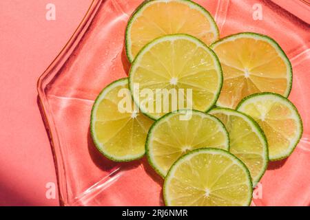 roues de chaux tranchées vert vif sur plaque de verre rose, fond Banque D'Images