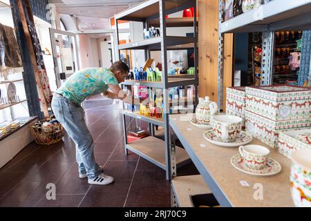 Signes et symboles, magasin de tourisme, Dalarna design de Suède, Falun, Suède. Sur la photo : Anders Ferm, PDG et propriétaire, arrange les chevaux de dala sur l'étagère dans le magasin. Banque D'Images