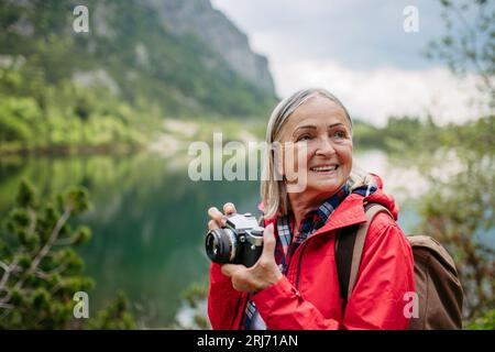 Potrait de femme senior active sur la randonnée dans les montagnes d'automne prenant des photos avec l'appareil photo. Banque D'Images