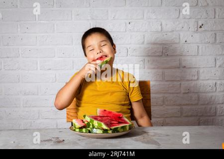 Savourez les moments les plus juteux de l'été, une bouchée de pastèque à la fois. Boy aime la pastèque Banque D'Images