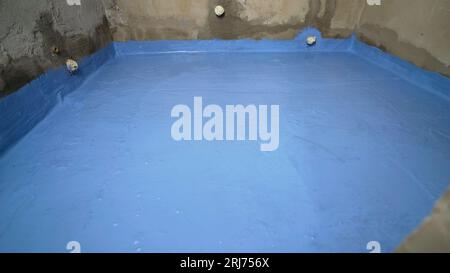 Appliquer de la peinture imperméable au sol. Imperméabilisation du sol dans une maison privée, application de résine liquide au sol, chape de béton et Banque D'Images
