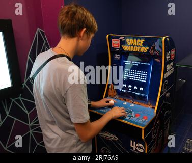 Machine de jeu Taito envahisseurs de l'espace. Simple Space Arcade dans le vieux jeu vidéo rétro 8 bits. Garçon joue à la machine à sous classique. Varsovie, Pologne - 28 juillet 2023. Banque D'Images