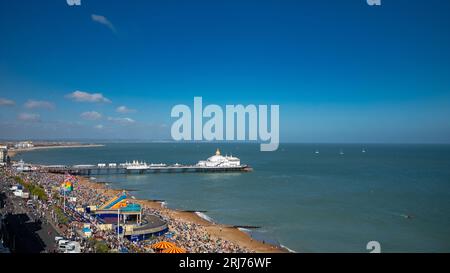 Une vue surélevée donnant sur une plage bondée d'Eastbourne, le front de mer et Eastbourne Pier lors d'une journée d'été glorieuse. East Sussex, Royaume-Uni. Banque D'Images