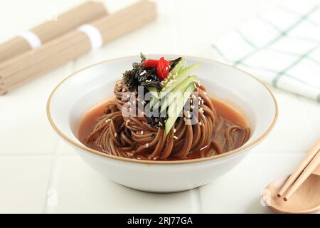 Bibim Naengmyeon nouilles Soba, soupe froide au sarrasin ou Guksu, nouilles épicées coréennes avec Gochujang. Sur la table blanche Banque D'Images