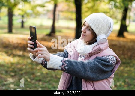 Une femme tient un téléphone et une tasse de boisson chaude. Femme prenant selfie sur smartphone. Banque D'Images