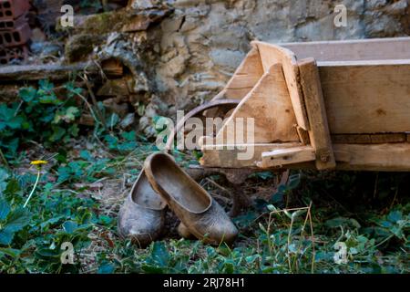 Scène rurale, sabots en bois reposant sur une brouette de travail dans une cour d'une maison castillane Banque D'Images