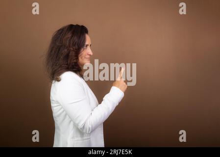 Portrait d'une femme d'entraînement faisant un geste de la main. Concept de gestionnaire démocratique et motivant. Isolé sur fond marron. Banque D'Images