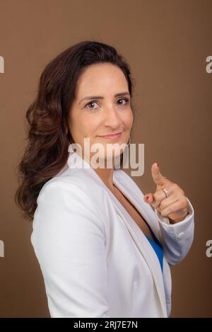 Portrait d'une femme d'entraînement faisant un geste de la main. Concept de gestionnaire démocratique et motivant. Isolé sur fond marron. Banque D'Images