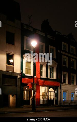 Londres, Royaume-Uni - décembre 23 2006 : façade d'une maison de ville à Soho Square enveloppée d'un énorme ruban rouge et éclairée par le lampadaire juste à côté doo Banque D'Images