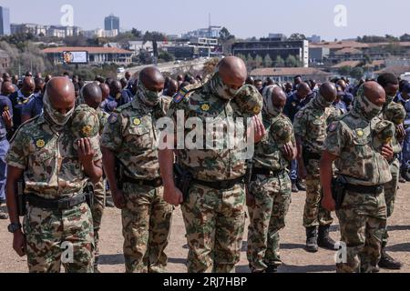 Johannesburg, Afrique du Sud. 21 août 2023. Les membres du Groupe de travail spécial sud-africain retirent leurs chapeaux et se dressent lors d’une prière lors de l’exposition de préparation des forces de sécurité qui protègent le sommet des BRICS à Innes Free Park le 21 août 2023, à Johannesburg, en Afrique du Sud. L'emplacement du sommet, le quartier de Sandton peut être vu en arrière-plan. Crédit : UPI/Alamy Live News Banque D'Images