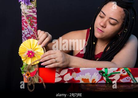 Photo de belle femme avec des tresses dans les cheveux à l'intérieur d'un cadre orné de fleurs et de tissus colorés dans une position horizontale touchant les fleurs Banque D'Images