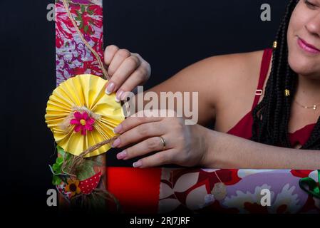 Photo de belle femme avec des tresses dans les cheveux à l'intérieur d'un cadre orné de fleurs et de tissus colorés dans une position horizontale touchant les fleurs Banque D'Images