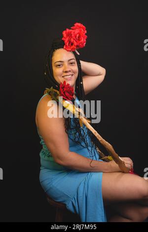 Belle femme avec des tresses dans les cheveux tenant un hula Hoop et plaçant une rose rouge sur sa tête. Personne positive. Isolé sur fond noir. Banque D'Images