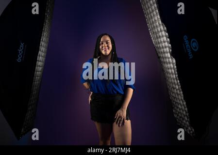 Portrait en studio d'une femme avec des tresses dans les cheveux portant des vêtements bleus et des shorts noirs entre deux stripboxes. Isolé sur fond bleu foncé. POS Banque D'Images