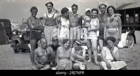 Années 1920, historique, estivale et une grande famille se réunissent pour une photo de groupe sur une plage, USA, montrant les modes de maillots de bain masculins et féminins de l'époque. Banque D'Images