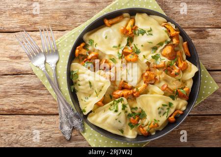 Portion de pâtes triangoli farcie de champignons chanterelles, oignons et herbes en gros plan dans une assiette sur la table. Vue de dessus horizontale Banque D'Images