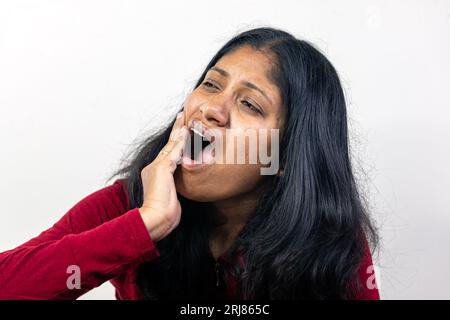 Une jeune femme tient sa main à sa joue dans la douleur alors qu'elle éprouve un mal de dents Banque D'Images