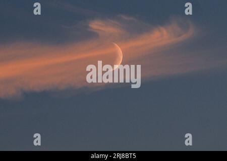 21 août 2023, Rhénanie du Nord-Westphalie, Mönchengladbach : la lune cireuse jette un coup d'œil sous les nuages, les nuages illuminés par le soleil couchant. Jusqu'à mercredi inclus, il restera estival en NRW avec des températures d'environ 28 degrés. Jeudi, le temps change alors, a déclaré un météorologue du Service météorologique allemand (DWD) lundi à Essen. De fortes pluies et des orages sont alors également possibles. Vers vendredi et le week-end, le temps sera variable et plus frais avec des températures maximales de 23 degrés. Photo : Federico Gambarini/dpa Banque D'Images