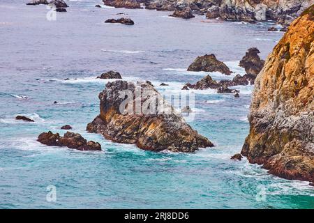 Belle falaise rugueuse escarpée aérienne de l'océan Pacifique s'écrasant contre la côte dure de Californie Banque D'Images