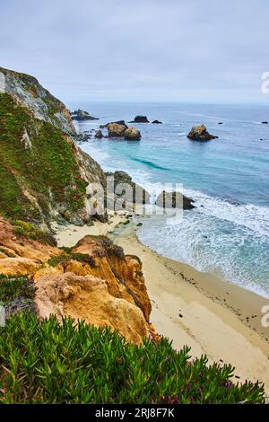 Colline verdoyante et pittoresque avec rivage sablonneux en contrebas et vagues de l'océan s'écrasant sur le rivage Banque D'Images