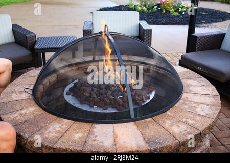 Gros plan d'un feu dans un foyer de brique couvert sur un patio dans un hôtel avec des chaises tout autour. Banque D'Images