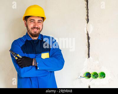 Portrait de travailleur ou d'ingénieur en vêtements de travail bleus et casque de sécurité jaune avec espace pour le texte. Un homme sur un chantier de construction tient une str d'isolation Banque D'Images