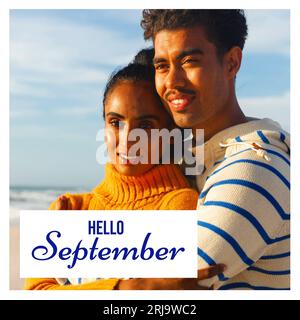 Composite de texte bonjour septembre sur couple biracial sur la plage Banque D'Images