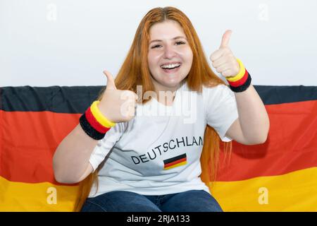 Belle fan de football féminin allemand avec drapeau de l'Allemagne à l'intérieur à la maison Banque D'Images