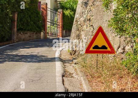 Panneau routier triangulaire de route bosselée. Il s'agit d'un signe de danger qui annonce une route déformée, en mauvais état, inégale ou avec une chaussée irrégulière. Banque D'Images