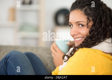 femme blottie sur le canapé avec une boisson chaude Banque D'Images