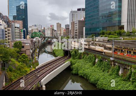 TOKYO, JAPON - AOÛT 09 2023 : trains passant par une intersection animée et un tunnel sur la rivière Kanda au pont Hijiribashi, Tokyo, Japon Banque D'Images