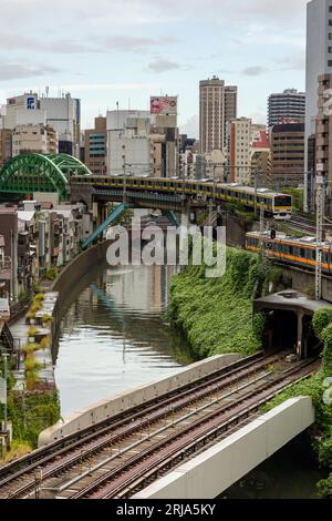 TOKYO, JAPON - AOÛT 09 2023 : trains passant par une intersection animée et un tunnel sur la rivière Kanda au pont Hijiribashi, Tokyo, Japon Banque D'Images