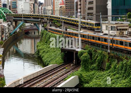 TOKYO, JAPON - AOÛT 09 2023 : trains passant par une intersection animée et un tunnel sur la rivière Kanda au pont Hijiribashi, Tokyo, Japon Banque D'Images