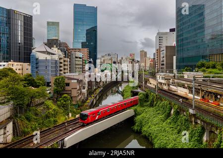 TOKYO, JAPON - AOÛT 09 2023 : trains passant par une intersection animée et un tunnel sur la rivière Kanda au pont Hijiribashi, Tokyo, Japon Banque D'Images