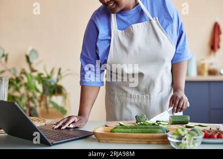 Gros plan d'une femme noire portant un tablier dans la cuisine et regardant la vidéo de cuisine en ligne, copier l'espace Banque D'Images