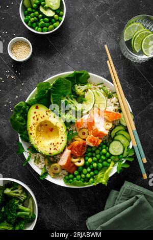 Bol à avocat au saumon avec brocoli, pois verts, riz et salade fraîche. Nourriture saine, vue de dessus Banque D'Images