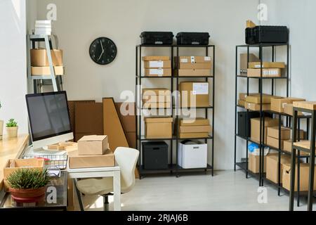 Partie d'entrepôt spacieux avec étagères et piles de boîtes en carton emballées Banque D'Images