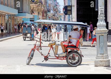 La Havane, Cuba, un homme est assis sur un bicitaxi ou un pousse-pousse attendant les clients. Transport petite entreprise dans la capitale Banque D'Images